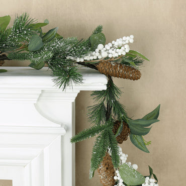 mr crimbo frosted garland featuring pine cones and berry clusters draped over fireplace mantel corner with sand colour wallpaper in the background