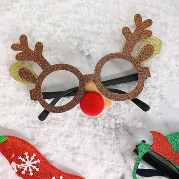 reindeer antler glitter glasses with red pom pom nose styled on white background with snow