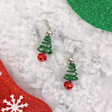 green spiral christmas tree earrings with red jingle bell on snow covered background