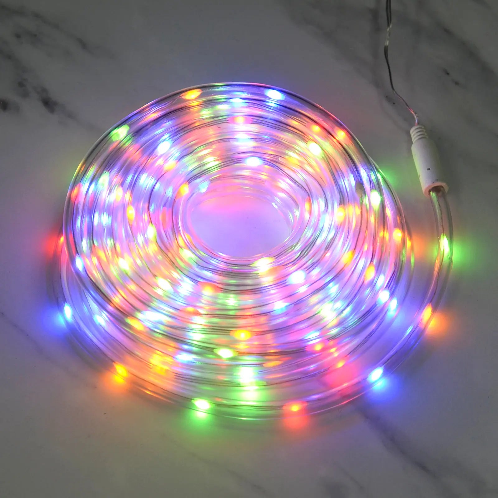 Coil of multicolour LED rope light lit up on a marble floor