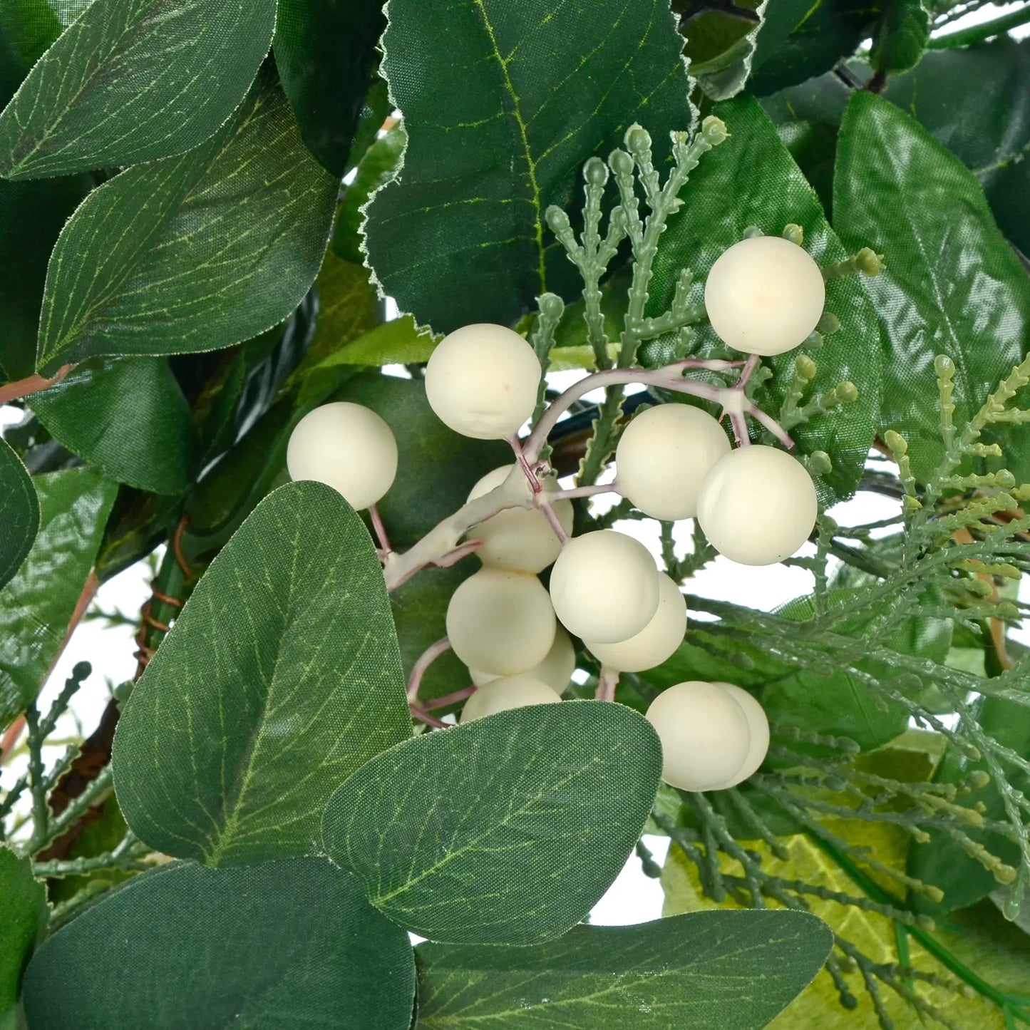 detail shot of white berry clusters nestled amongst green pe and silk foliage
