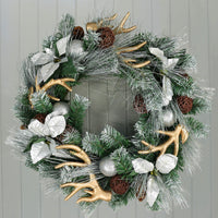silver christmas wreath with gold antlers hanging on grey wooden door