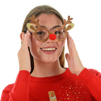 model wears brown glasses shaped like reindeer antlers featuring glitter finish and red pom pom nose