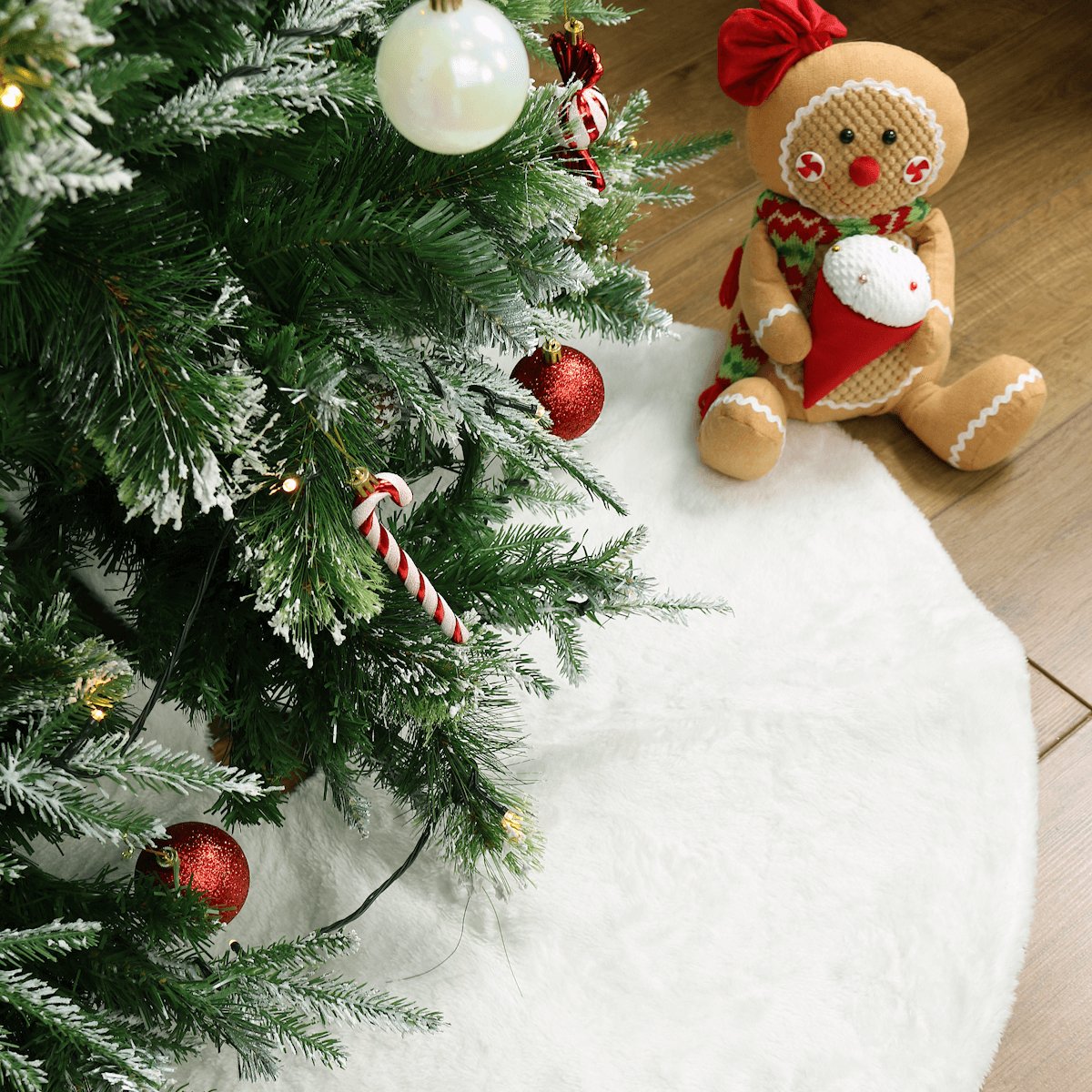 christmas tree skirt on wooden floor in white finish with red and white christmas tree decorations and gingerbread girl decoration