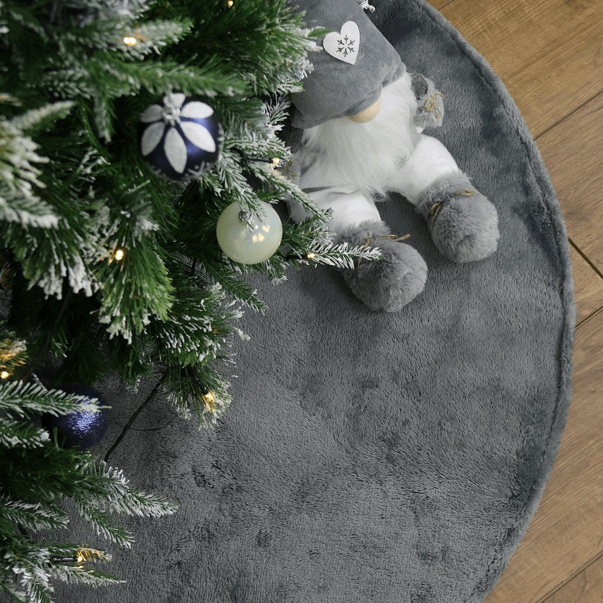 grey christmas tree skirt underneath tree styled with navy and white tree decorations with grey gonk figure