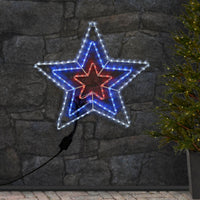 large triple star outdoor rope light silhouette with white, blue and red LED lights on a patio wall with Christmas tree in pot