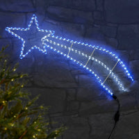 Blue and white shooting star rope light Christmas garden decoration on a stone wall with Christmas tree