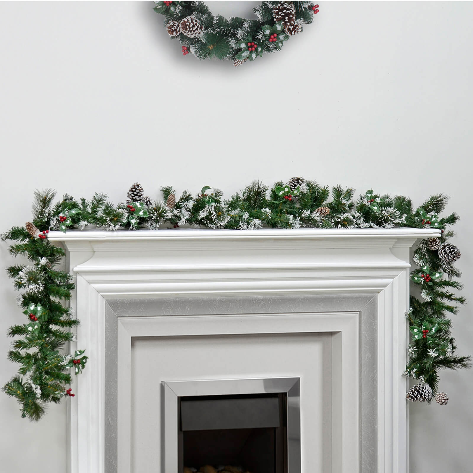 Luxury Frosted pine Christmas garland with pine cones and red berries on a white mantelpiece