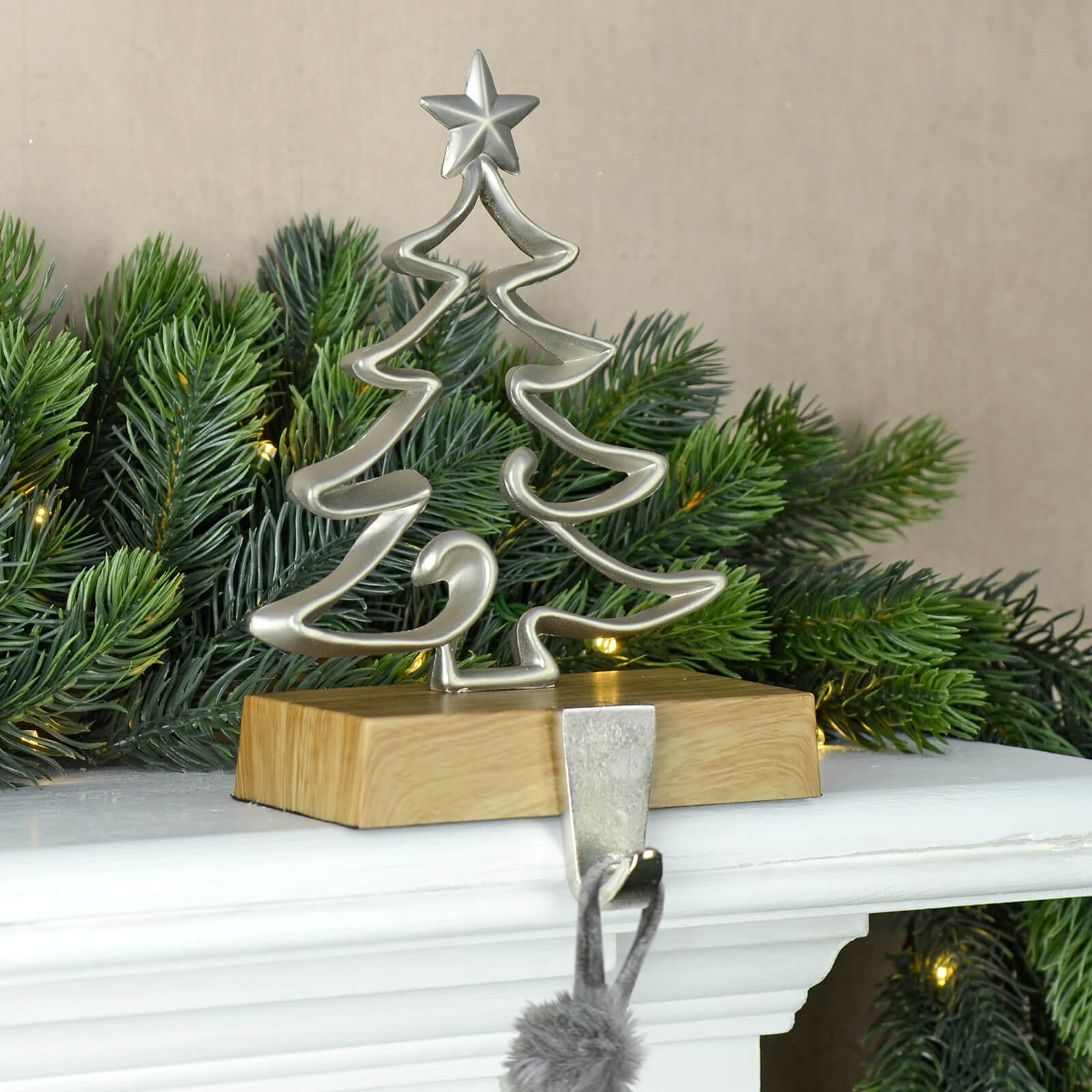 Mr Crimbo tree shaped silver metal Christmas stocking holder with star on a mantelpiece with Christmas garland