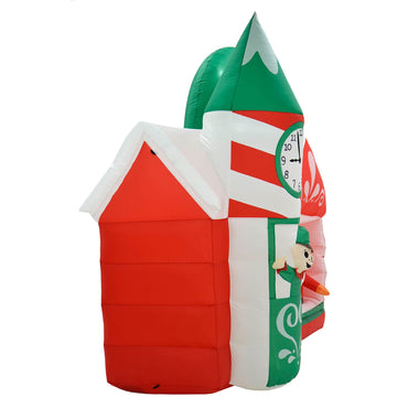 Side view of green and red light up inflatable Santa's workshop Christmas decoration with candy cane tower and clock