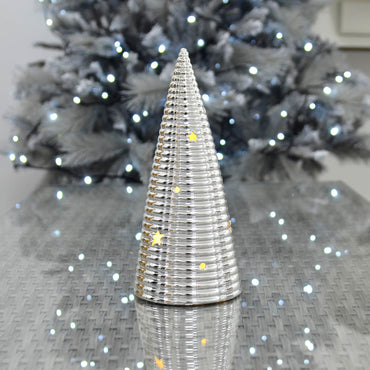Light up Christmas tree silver ornament with warm white LED lights, cut away stars and baubles on a grey glass topped table reflecting ice white fairy lights