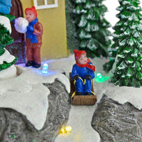 Close up detail of child sledging and child with snowball on a Christmas snow scene ornament with coloured LED lights and glittering snow