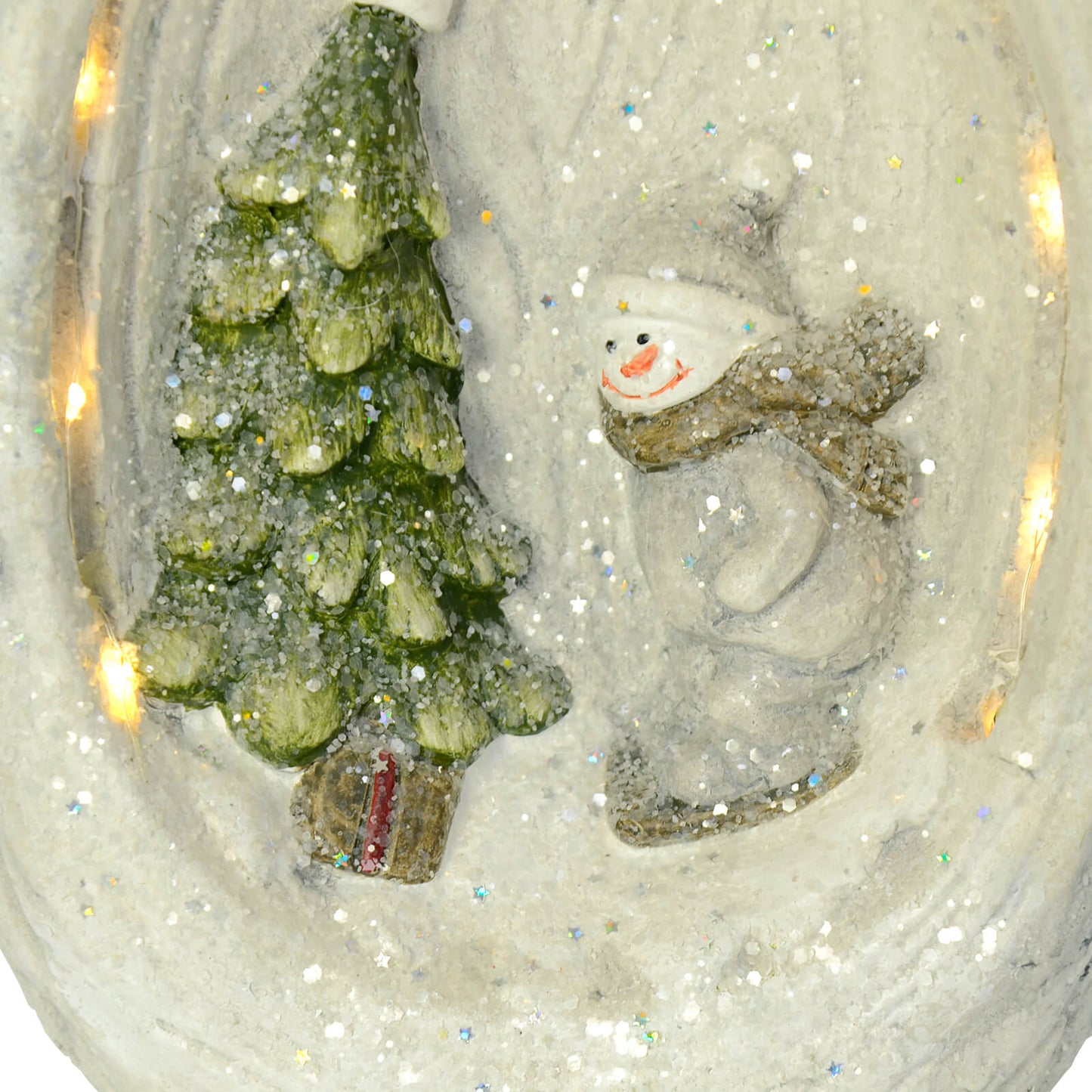 Close up detail of snowman and Christmas tree on a ceramic Santa ornament, covered in iridescent star and hexagon glitter shapes