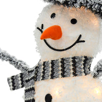 Close up of the face of a large LED snowman Christmas decoration with warm white LED lights, orange felt carrot nose, black grey and white knitted scarf and black button eyes