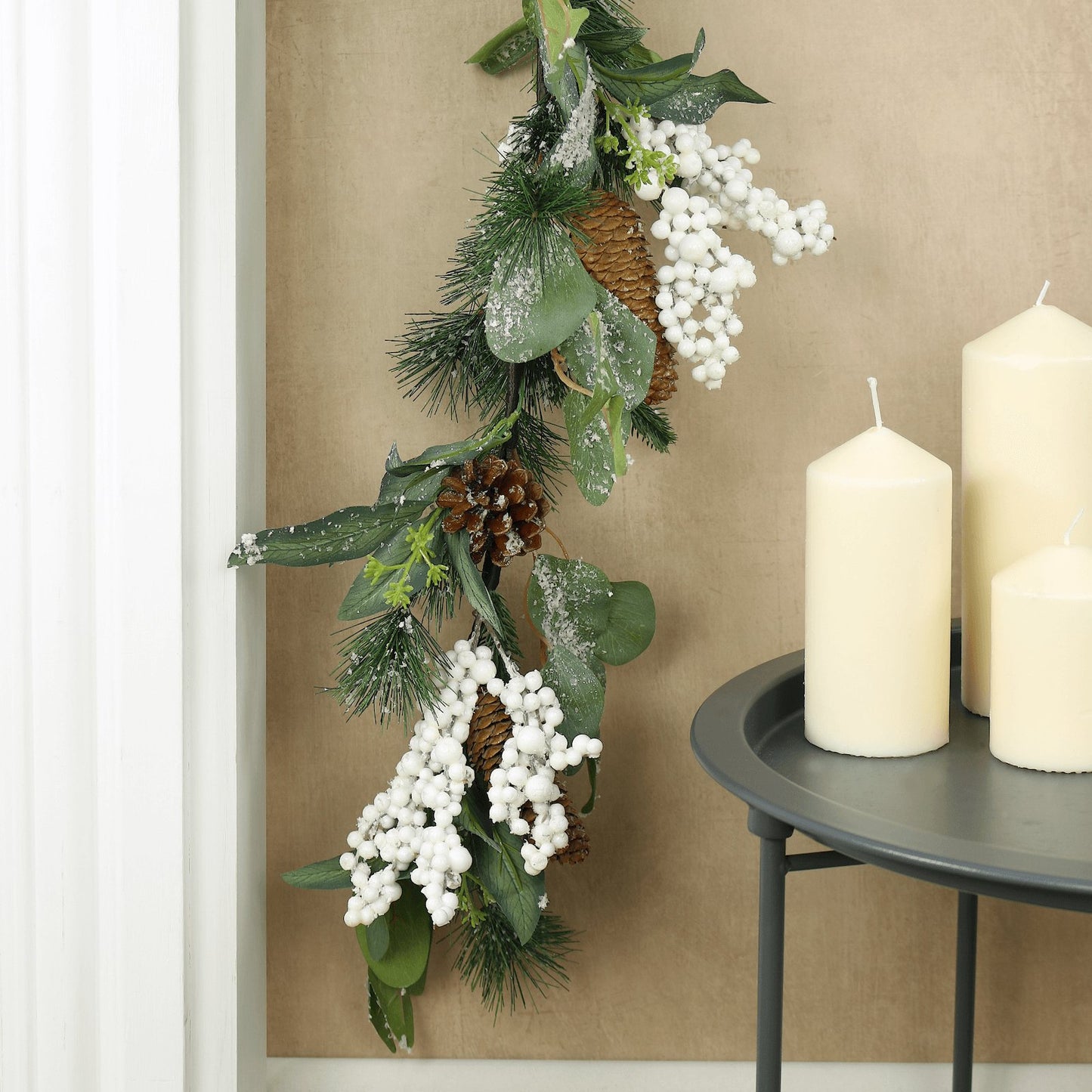 mr crimbo garland hanging down from fireplace mantel styled beside tray table featuring white pillar candles