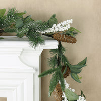 mr crimbo frosted garland featuring pine cones and berry clusters draped over fireplace mantel corner with sand colour wallpaper in the background
